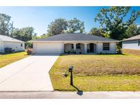 Charming single-story home with a well-manicured lawn, attached garage, and inviting front porch with decorative columns at 2903 Pope St, North Port, FL 34287