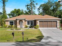 Charming single-story home featuring a well-manicured lawn and a two-car garage at 3621 Jade St, North Port, FL 34288