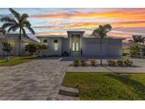 Beautiful single story home with lush landscaping, brick driveway, and sunset sky at 3712 Carmichael Dr, Punta Gorda, FL 33950