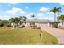 Inviting home featuring a well-kept lawn, mature palm trees, and a brick driveway at 441 Norma Ct, Punta Gorda, FL 33950
