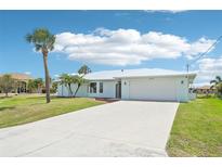 Inviting single-story home featuring a well-manicured lawn, beautiful palm trees, and a clean white driveway at 5194 Cooper Ter, Port Charlotte, FL 33981