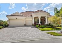 Beautiful single-story home with a red tile roof, a three-car garage, and a paved brick driveway at 5428 Royal Poinciana Way, North Port, FL 34291