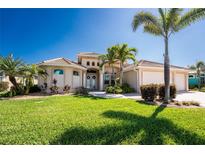 Beautiful home featuring a tile roof, manicured lawn, and tropical landscaping in a desirable neighborhood at 15762 Aqua Cir, Port Charlotte, FL 33981