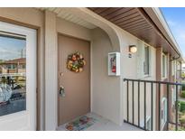 Condo front door with wreath, welcome mat, neutral paint, and black metal railing at 25100 Sandhill Blvd # R202, Punta Gorda, FL 33983