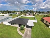 A charming home with a fenced yard and well-maintained landscaping set in a beautiful neighborhood with cloudy skies at 3324 Port Charlotte Blvd, Port Charlotte, FL 33952