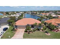 Beautiful waterfront home featuring a tile roof, brick driveway, two-car garage, and well-maintained landscaping at 584 Toulouse Dr, Punta Gorda, FL 33950