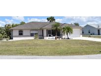Charming single-story home with well-maintained lawn and tropical landscaping showcasing curb appeal at 21342 Walling Ct, Port Charlotte, FL 33954