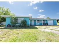 Inviting one story home with attached garage, covered entry and bright teal colored siding at 2230 Harbor Blvd, Port Charlotte, FL 33952