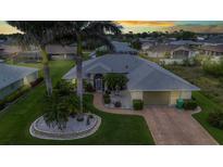 Beautiful single-story home featuring lush landscaping, palm trees, and a brick driveway at 23104 Turnbull Ave, Port Charlotte, FL 33954