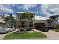 Stunning two-story home featuring lush landscaping, a paver driveway, and a metal roof at 48 Colony Point Dr, Punta Gorda, FL 33950