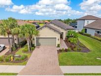 Beautiful single-Gathering home showcasing a lush landscaped yard and inviting brick-paved driveway leading to the two-car garage at 8725 Amaretto Ave, Sarasota, FL 34238