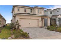 Two-story home featuring a neutral color scheme, attached garage and a driveway made of paving stones at 15975 Mulrion Blvd, Punta Gorda, FL 33982