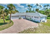 Charming single-story home with paver driveway and lush landscaping, including tall palm trees at 17506 Cape Horn Blvd, Punta Gorda, FL 33955