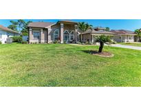 Expansive front yard featuring a well-manicured lawn and meticulously maintained landscaping at 420 Wabash Ter, Port Charlotte, FL 33954