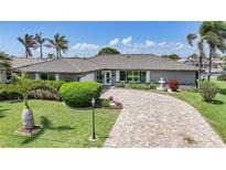 Charming home featuring a beautifully landscaped front yard, a fountain, and a circular paver driveway at 505 Via Cintia, Punta Gorda, FL 33950