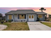 Charming single-story home featuring a well-manicured lawn and a cozy front porch with white picket fence at 5121 Chaves Cir, Port Charlotte, FL 33948