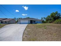 Charming single-story home featuring an attached two-car garage and a well-manicured lawn on a sunny day at 7225 Sea Mist Dr, Port Charlotte, FL 33981