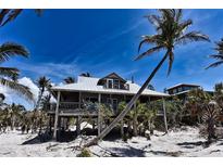 Charming elevated beach house with weathered wood exterior and metal roof near palm trees at 8754 King St, Placida, FL 33946