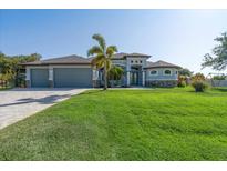 Beautiful, well-manicured lawn and a lovely two-story home with a three-car garage and custom front door at 13443 Boabadilla Ln, Port Charlotte, FL 33981