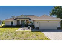 Charming single-story home featuring a landscaped front yard, a two-car garage, and a covered entryway with double doors at 1606 Navigator Rd, Punta Gorda, FL 33983