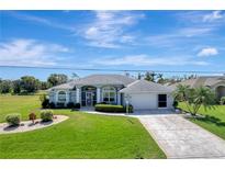 Well-maintained single-story home features a beautifully landscaped lawn and a spacious driveway leading to an attached garage at 229 Sportsman Rd, Rotonda West, FL 33947