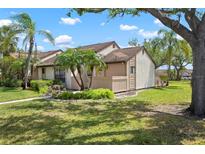 Charming exterior view showcases a well-manicured lawn, complemented by lush tropical landscaping, including mature palm trees at 5390 Brassy Loop, North Port, FL 34287
