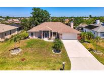 Charming single-story home with a well-manicured lawn, complemented by mature trees and a long driveway at 452 Greenwich Nw Ave, Port Charlotte, FL 33952