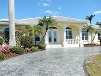 Stunning home entrance featuring a decorative driveway, lush landscaping, and a stylish front door with architectural pillars at 15490 Seafoam Cir, Port Charlotte, FL 33981