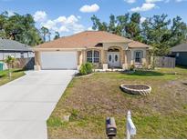Charming single-story home with a well-manicured lawn, covered entryway, and two-car garage at 16450 Bauers Ave, Port Charlotte, FL 33954