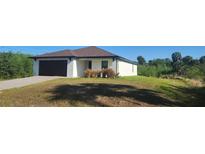 Beautiful one-story home featuring a dark brown roof, a black garage door and well-maintained landscaping at 17374 Gadsen Ave, Port Charlotte, FL 33948