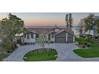 Stunning waterfront home featuring lush landscaping, brick driveway, and a charming tile roof at 1820 Jamaica Way, Punta Gorda, FL 33950