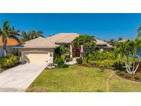 Beautiful single-story home featuring lush landscaping, well manicured lawn, and a tile roof with a two car garage at 211 Lido Dr, Punta Gorda, FL 33950