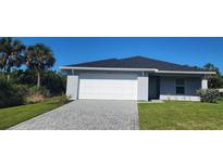 Charming single-story home with a two-car garage, landscaped lawn, and a paved driveway at 4071 Conestoga St, Port Charlotte, FL 33948