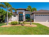 Well-manicured home featuring a three-car garage, tropical landscaping, and a paver driveway at 4174 Perch Cir, Port Charlotte, FL 33948