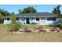 Charming single-story home with a light blue exterior, a well-kept lawn and front garden with an arched entryway at 1233 Dewhurst St, Port Charlotte, FL 33952