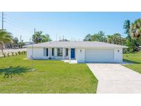 Charming single-story home with a well-maintained lawn and a classic blue front door at 1795 Elinor Pl, Englewood, FL 34223