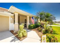 Inviting front porch with American flag, lush landscaping, and a welcoming entrance at 1991 Mossy Oak Dr, North Port, FL 34287