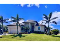 Beautiful single-story home with a well-manicured lawn and tropical landscaping, including palm trees at 24103 Pyramid Way, Punta Gorda, FL 33955