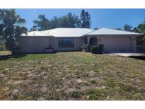 Single Gathering home featuring a metal roof, lush landscaping, and an attached two car garage at 243 Harbor Blvd, Port Charlotte, FL 33954