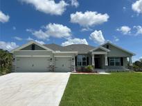 Charming single-story home featuring a three car garage, well-manicured lawn, and beautiful landscaping at 25156 Rosamond Ct, Punta Gorda, FL 33983