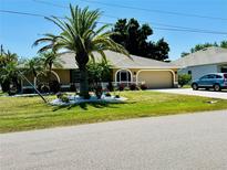 Charming single-story home featuring a well-manicured lawn, mature palm tree and colorful flowerbeds enhancing curb appeal at 25263 Padre Ln, Punta Gorda, FL 33983