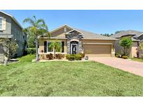 Charming single-story home featuring a stone facade, manicured lawn, and lush landscaping at 27854 Arrowhead Cir, Punta Gorda, FL 33982