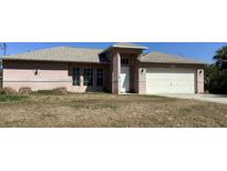 Charming single-story home with a two-car garage, light pink exterior, and well-lit entry at 3293 Cincinnati St, North Port, FL 34286