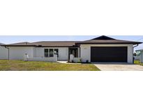 Charming single-story home with white exterior, black door/trim and well-manicured lawn at 3315 Elkcam Blvd, Port Charlotte, FL 33952