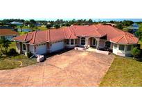 Spacious waterfront home featuring a large driveway, tile roof, and attached garages at 730 Boundary Blvd, Rotonda West, FL 33947