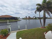 Picturesque waterfront view featuring canal, palm trees, and neighboring homes on a cloudy day at 2575 Brazilia Ct, Punta Gorda, FL 33950