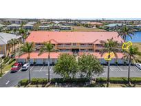 Condo building exterior with parking, landscaping, palm trees, and partial water view at 3228 Purple Martin Dr # 116, Punta Gorda, FL 33950