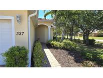 Inviting view of home's facade, showcasing the front yard with its lush landscaping and brick walkway at 327 Monaco Dr # 12, Punta Gorda, FL 33950