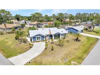Charming single-story blue home featuring a metal roof and a well-manicured front lawn in a beautiful community at 4474 Ozark Ave, North Port, FL 34287