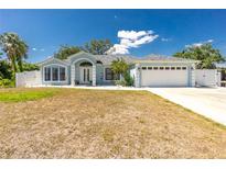 Charming one-story home with a two-car garage, light blue exterior paint, and well-manicured landscaping at 4569 Kenvil Dr, North Port, FL 34288